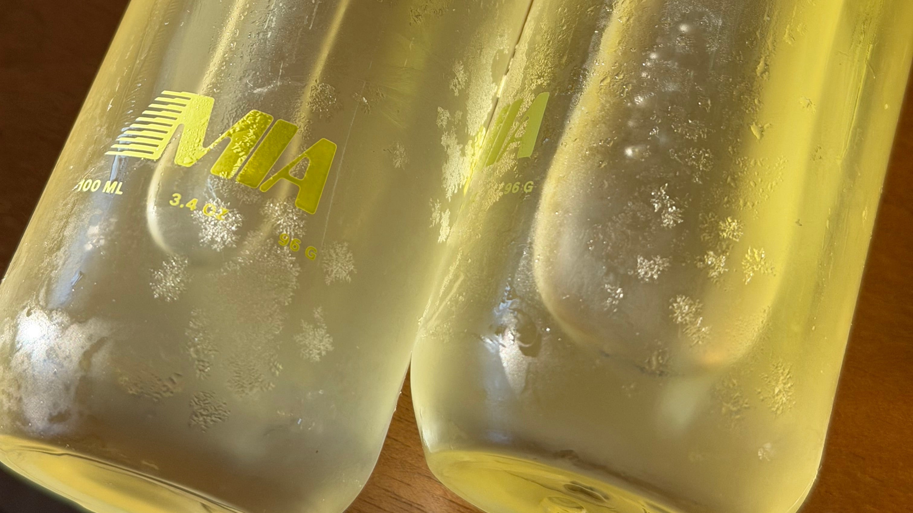 Two clear bottles with labels on a wooden surface