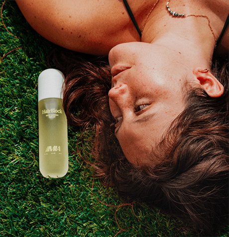 Person lying on grass with a bottle of alcohol nearby